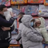 Orang-orang menggendong balita mereka melewati toko mainan di Beijing, Senin, 19 Januari 2026. (AP Photo/Andy Wong)