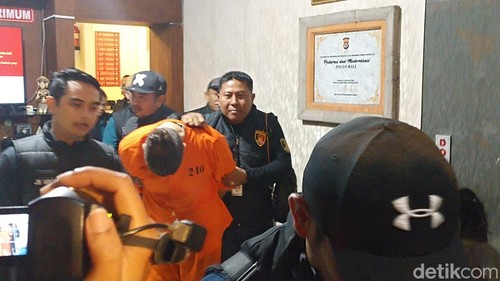 Buronan Interpol Costinel-Cosmin Zuleam menunduk saat digiring ke mobil tahanan di Polda Bali, Selasa (20/1/2026). (Foto: Abid Ahmad Ibrahim/detikBali)