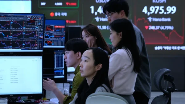 Para pedagang mata uang mengamati monitor di dekat layar yang menampilkan Indeks Harga Saham Komposit Korea KOSPI kanan atas di ruang perdagangan valuta asing kantor pusat Hana Bank di Seoul Korea Selatan Senin 2 Februari 2026 AP PhotoAhn Young joon