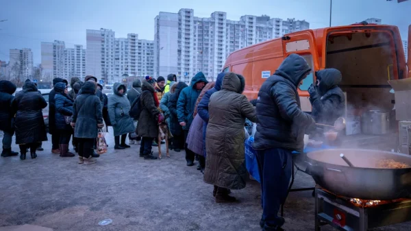 Warga yang mengalami pemadaman listrik di rumah mereka setelah serangan udara Rusia mengantre untuk menerima makanan panas gratis di lingkungan perumahan di Kyiv, Ukraina, Jumat, 30 Januari 2026. (AP Photo/Dan Bashakov)