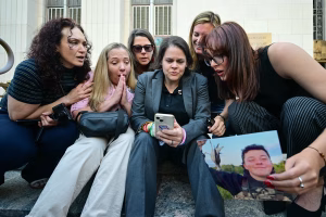 Laura Marquez-Garrett (C, blazer abu-abu), pengacara penggugat untuk SMVLC (Social Media Victims Law Center), berkumpul dengan orang tua dan anggota keluarga korban saat mereka bereaksi terhadap berita bahwa juri telah menyatakan Meta dan YouTube bertanggu(AFP)Layanan iklan