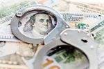 Handcuffs lying on american dollars, financial crime concept.